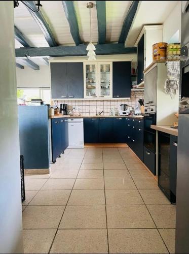 Il comprend une grande cuisine avec des placards bleus et du carrelage. dans l'établissement MAISON DE CHARME piscine chauffée, à Carlux