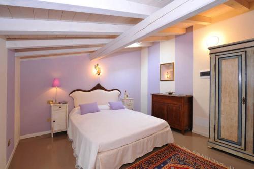 - une chambre avec un grand lit blanc aux murs violets dans l'établissement B&B La Mongolfiera, à Villafranca di Verona