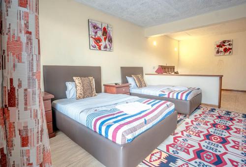a bedroom with two beds and a rug at Matteos Italian Restaurant,Bar & Accommodation in Naivasha