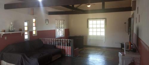a living room with a couch and two windows at Sítio jardim in São Pedro da Aldeia