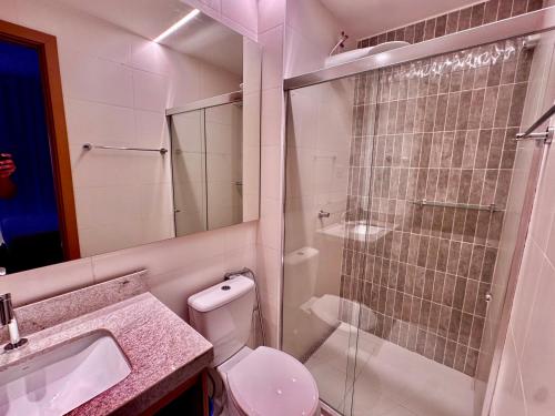 une salle de bain avec toilettes et douche en verre dans l'établissement Barra Ocean Apart, à Salvador