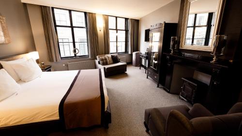 a hotel room with a bed and a chair and windows at B&B 't Poorthuys in Middelburg