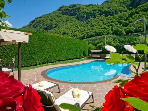 a swimming pool with chairs and a mountain in the background at Apartment Pienzenau by Interhome in Postal