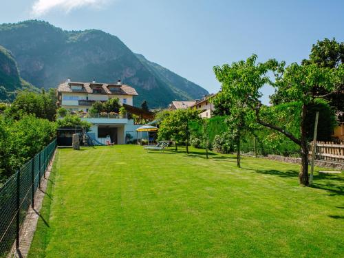 a green yard with a house and mountains in the background at Apartment Neuhaus by Interhome in Andrian