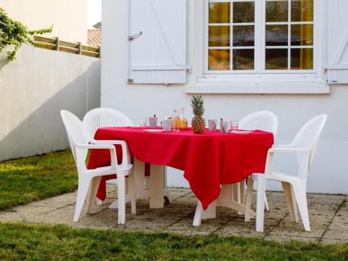 une table avec un chiffon rouge et des chaises blanches dans l'établissement Holiday Home Remagy by Interhome, à La Bernerie-en-Retz