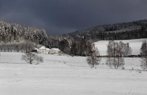 a snow covered field with a house in the distance at Penzion Krakovice in Kaplice