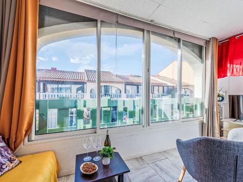 - un salon avec une grande fenêtre et des verres à vin sur une table dans l'établissement Apartment Parc de la Mer-12 by Interhome, au Barcarès