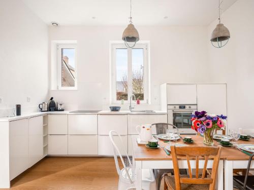 a white kitchen with a wooden table and chairs at Holiday Home La Floriette by Interhome in Dinard