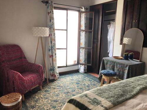 アンティグア・グアテマラにあるPoetry House Antigua Guatemalaのベッドと椅子と窓のある寝室