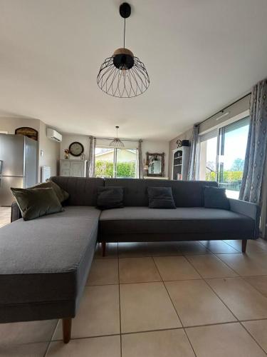- un canapé bleu dans le salon avec fenêtres dans l'établissement Gite des Pins, à Aureilhan
