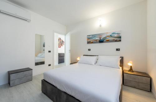 a white bedroom with a large bed and a mirror at Residence Villa Argentea in Gravedona