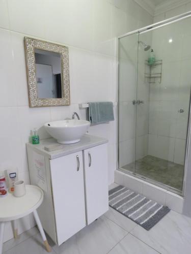 a white bathroom with a sink and a shower at Destiny Jeffreys bay in Jeffreys Bay