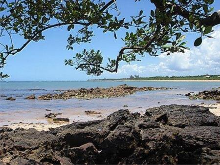 a view of a beach with rocks and the ocean at Casa para sua família in Aracruz