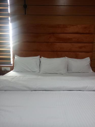 a bed with white pillows and a wooden headboard at Ja'Oak Hotel and Suites in Benin City