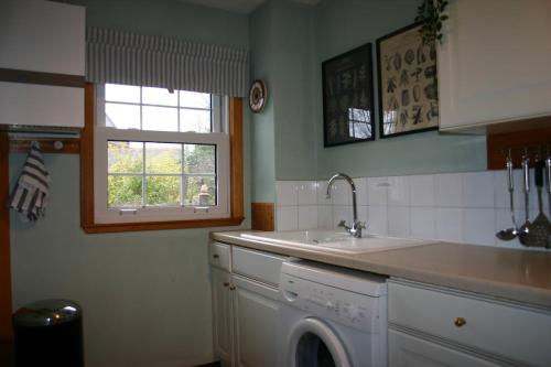a kitchen with a sink and a washing machine at Church Cottage with sunny garden in Ayr