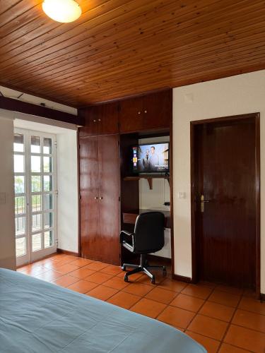 a bedroom with a bed and a chair and a television at Habitación con estacionamiento y baño privado in Funchal