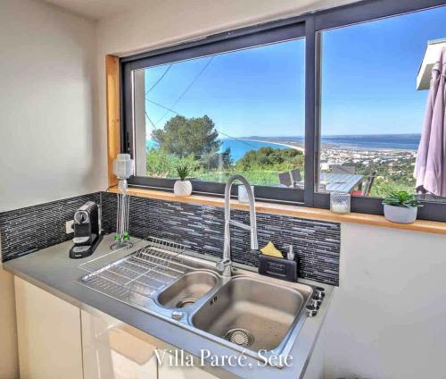 une cuisine avec un évier et une grande fenêtre dans l'établissement Villa Vue Mer, à Sète