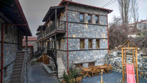 a large stone building with a wooden table in front of it at Suites Mouses in Palaios Agios Athanasios