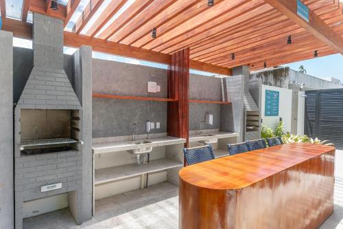 a outdoor kitchen with a wooden table and a fireplace at Paraíso familiar em frente a vila do pescador caboclo na nova orla de Tamandaré in Tamandaré