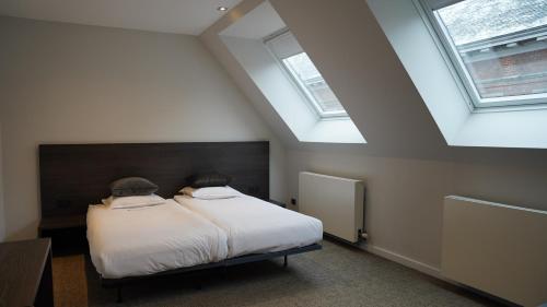 a bedroom with a bed and two skylights at Hotel Hof van Aragon in Lier