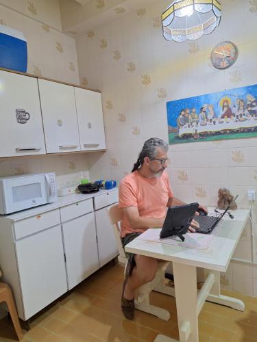 a man sitting at a table with a laptop at Apartamento Gracioso ao lado do Parque das Águas in Caxambu