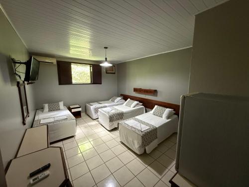 a living room with two beds and a tv at Hotel Mato Grosso Águas Quentes in Sucuri