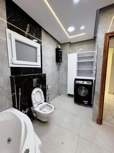 a bathroom with a toilet and a tv on the wall at Luxury three bedroom duplexSheraton Airport in Cairo