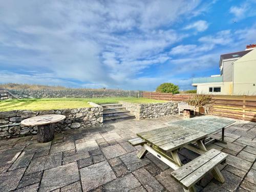 a picnic table and bench on a stone patio at BEACH SIDE Sea Shanty House in Trearddur