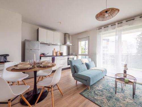 Il comprend une cuisine et un salon avec une table et un canapé bleu. dans l'établissement Le Cocon de Saint-Priest 1 Chambre Terrasse et Parking, à Saint-Priest