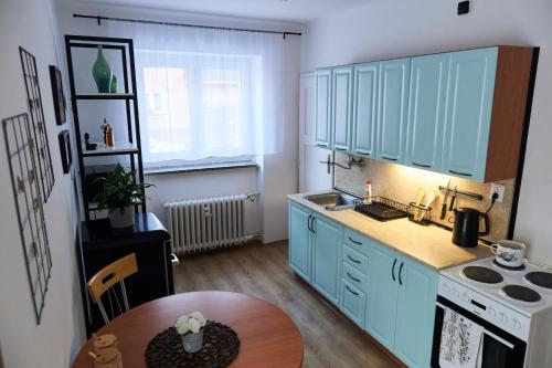 a kitchen with blue cabinets and a table in it at Sunny apartment Trutnov in Trutnov