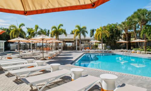 a swimming pool with white chairs and umbrellas at Sirata Saint Pete Beach in St Pete Beach