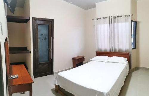 a bedroom with a white bed and a wooden table at El Paso de Almirante in Almirante