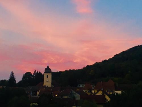 a sunset over a town with a clock tower at La Bonne Auberge in Clerval