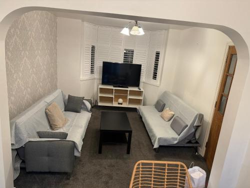 a living room with two couches and a flat screen tv at Cosy 5 Bedroom Central Birmingham in Birmingham
