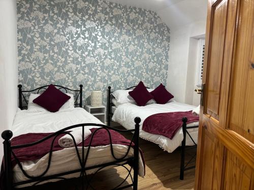 two beds in a bedroom with floral wallpaper at Cosy 5 Bedroom Central Birmingham in Birmingham