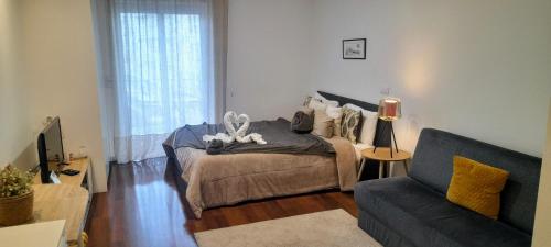 a bedroom with a bed and a living room with a couch at Ria Palace Apartment in Aveiro