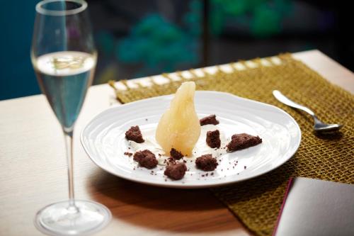 a white plate with a dessert and a glass of wine at Crowne Plaza Verona Fiera by IHG in Verona