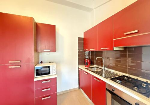 a kitchen with red cabinets and a microwave at Semplice BnB Bonagia in Valderice