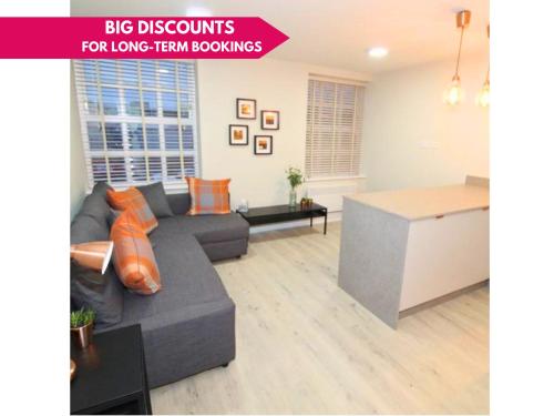 a living room with a gray couch and a kitchen at Charming Modern 2br Flat In Central Preston in Preston