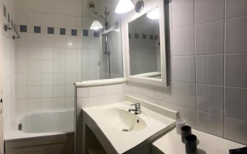 a bathroom with a sink and a mirror and a tub at Résidence Les Grands Pins - maeva Home - 2 Pièces 4 Personnes Sélection MAE-6962 in Maubuisson