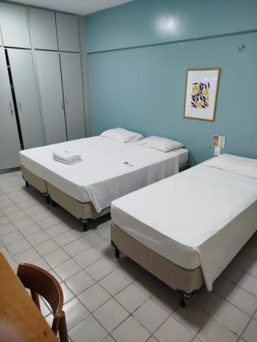 two beds in a room with a table and chairs at Nordeste Palace Hotel - Fortaleza in Fortaleza