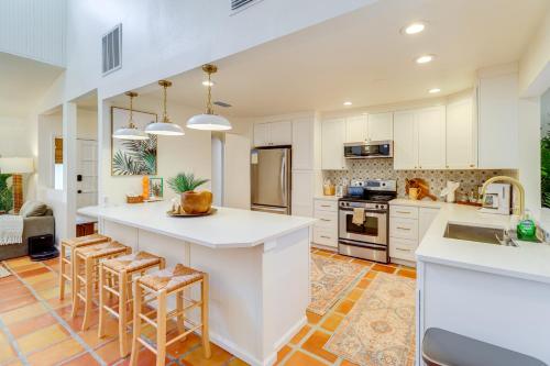 a kitchen with white cabinets and a large island with bar stools at Half-Mi to Private Beach Floridana Beach Getaway in Melbourne Beach