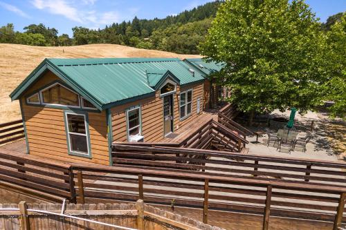 a wooden house with a green roof and a fence at Mendocino Redwoods RV Resort in Willits