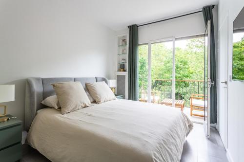 une chambre avec un grand lit et une grande fenêtre dans l'établissement Appartement Neuilly, à Neuilly-sur-Seine