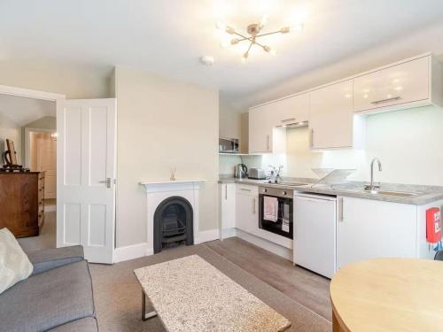 a kitchen and living room with white cabinets and a fireplace at Sea View Apartment Near The Beach and Town Center in Cromer
