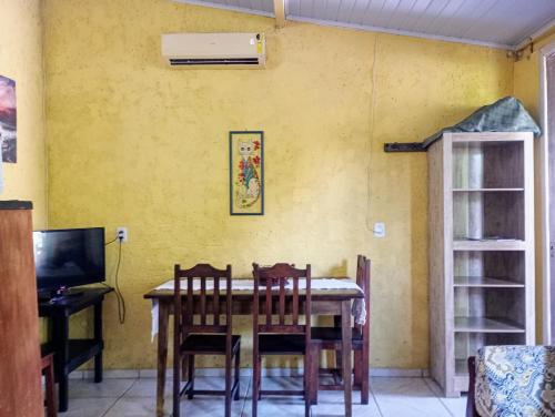 a dining room with a table and chairs against a yellow wall at Hibisco Rosa Aluguéis in Araçatuba