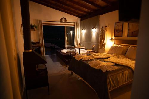 a bedroom with a large bed and a living room at Recanto Águas Nascentes - Chalé Casal com Hidromassagem in Pedra Menina