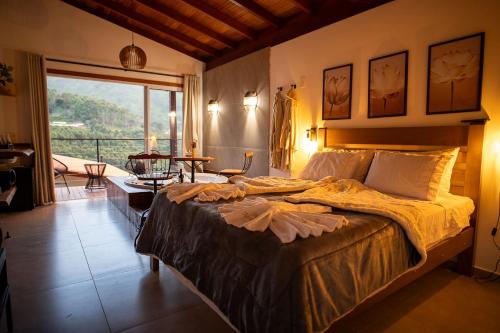 a bedroom with a large bed and a large window at Recanto Águas Nascentes - Chalé Casal com Hidromassagem in Pedra Menina