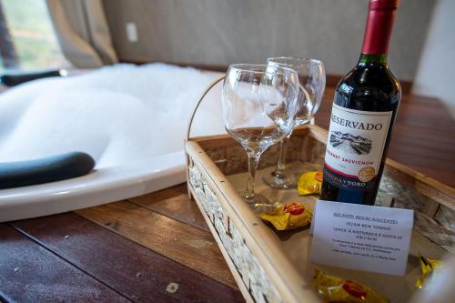 a bottle of wine and a wine glass on a table at Recanto Águas Nascentes - Chalé Casal com Hidromassagem in Pedra Menina