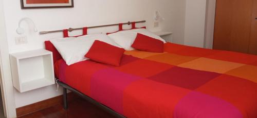 een kleurrijk bed met twee rode kussens in een kamer bij A casa di A in Milaan